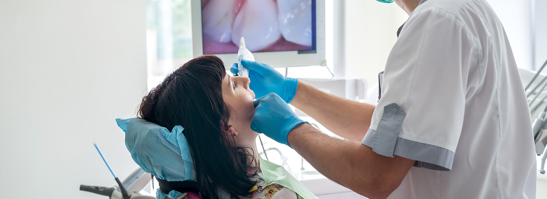 A dental professional performing a procedure on a patient s mouth while wearing protective gloves and a surgical mask.